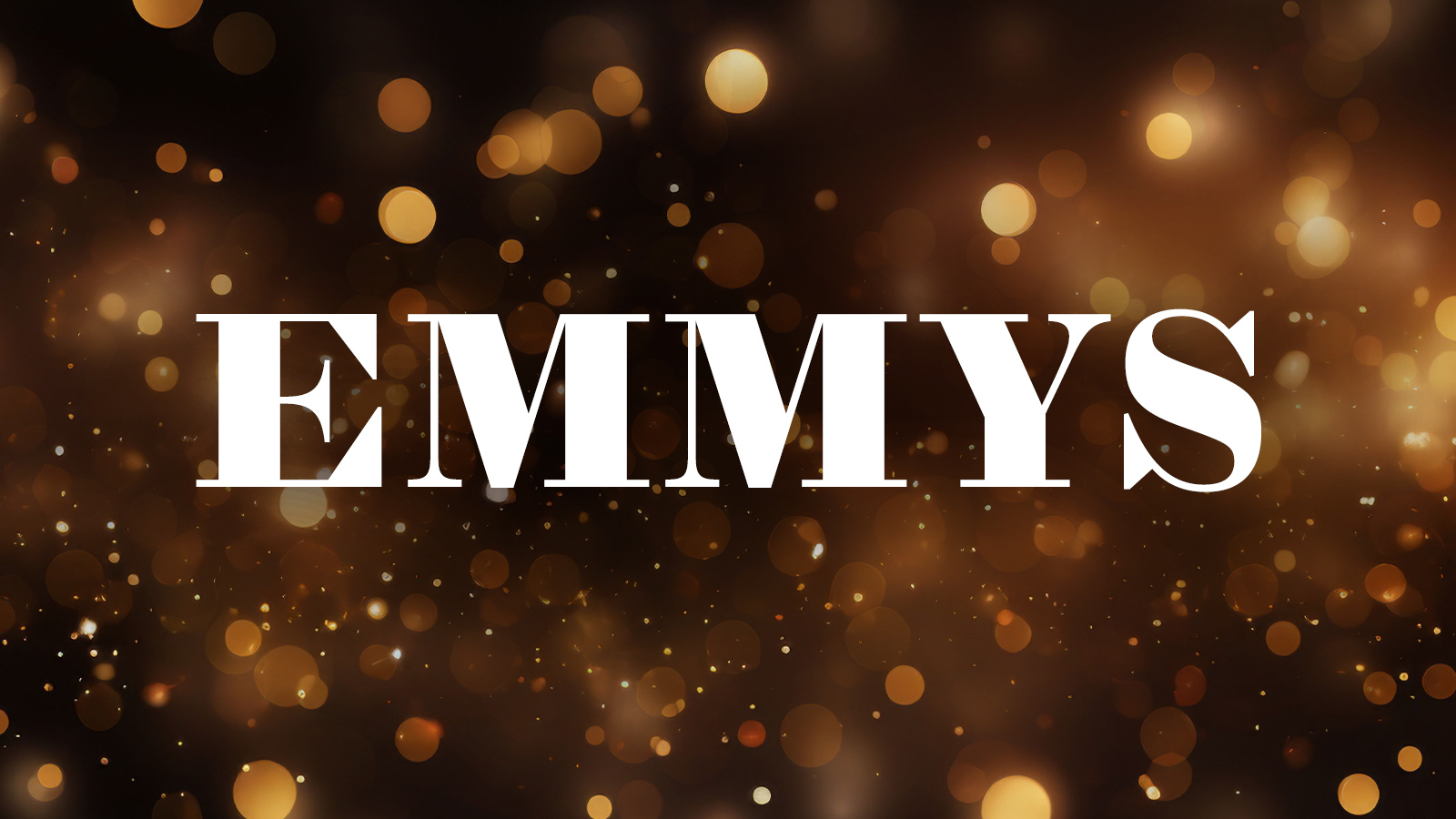 The word 'EMMYS' appears in block white text over a dark, blurred scene filled with warm, glowing lights in shades of gold, orange, and brown.