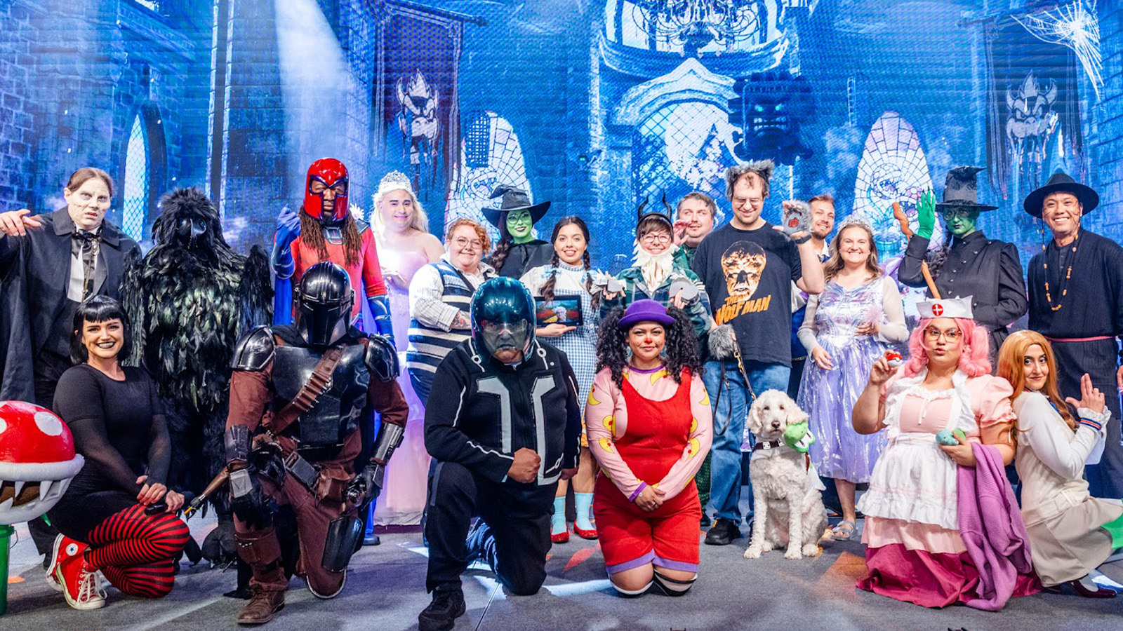 A group of staff members pose for the camera dressed in Halloween costumes including Glinda and Elphaba, the Mandalorian, Loonette the Clown, and more.