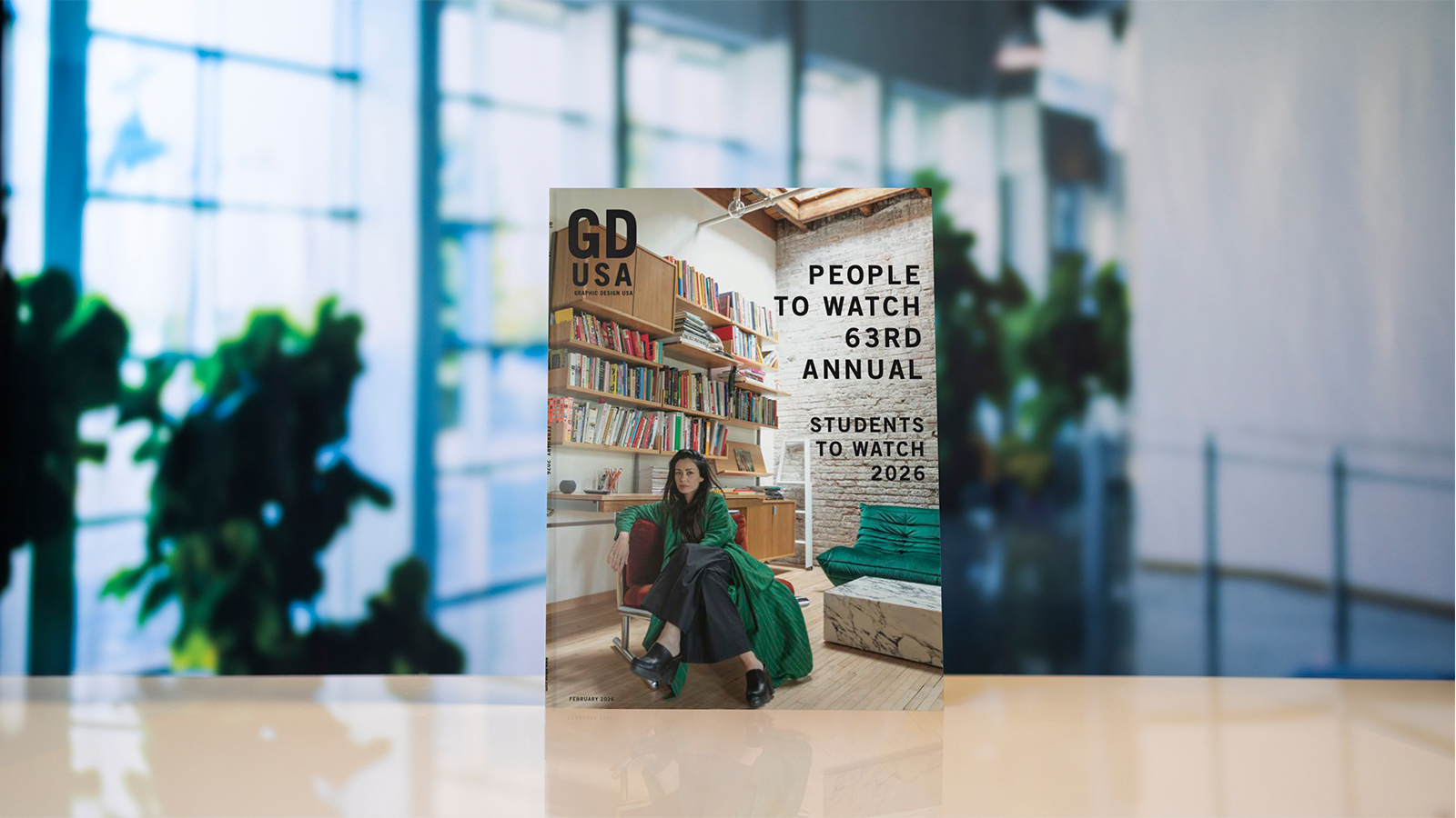 The cover of ‘Graphic Design USA’ featuring a designer sitting in a loft and the words People to Watch 63rd Annual and Students to Watch 2026.
