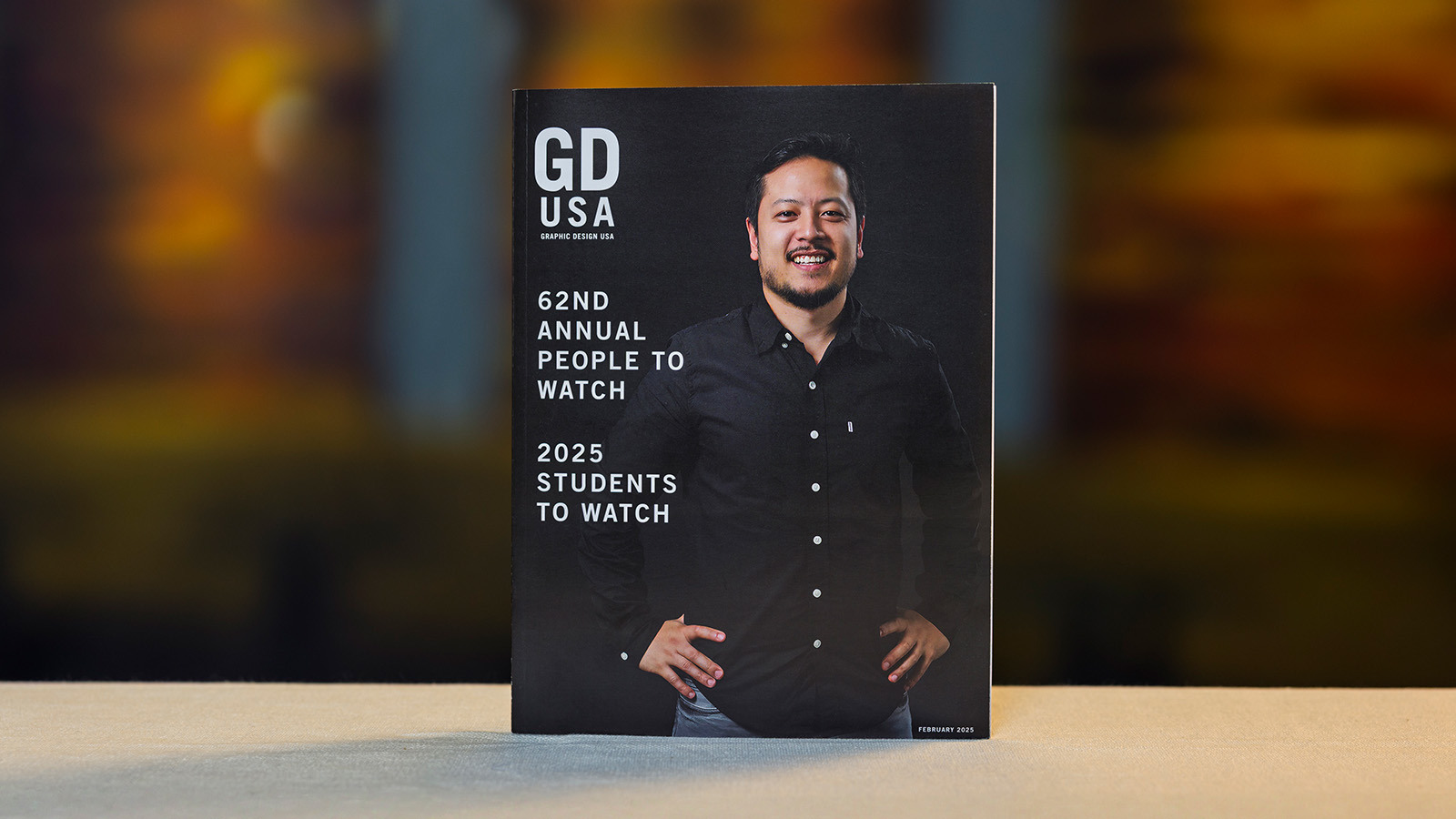 The February 2025 print issue of ‘Graphic Design USA.’ The cover features a smiling designer and text that reads “62nd Annual People to Watch” and “2025 Students to Watch.”