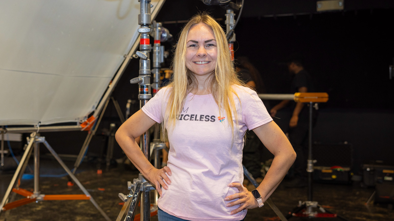 Director Sarah Goras stands confidently while smiling on set during filming in a Full Sail soundstage.