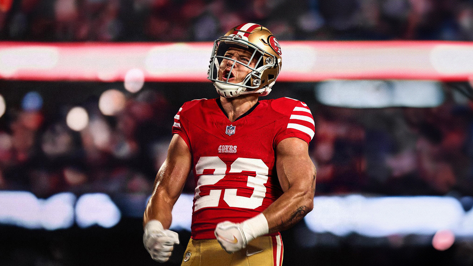 A football player in a red San Francisco 49ers jersey, number 23, celebrating passionately on the field with clenched fists.