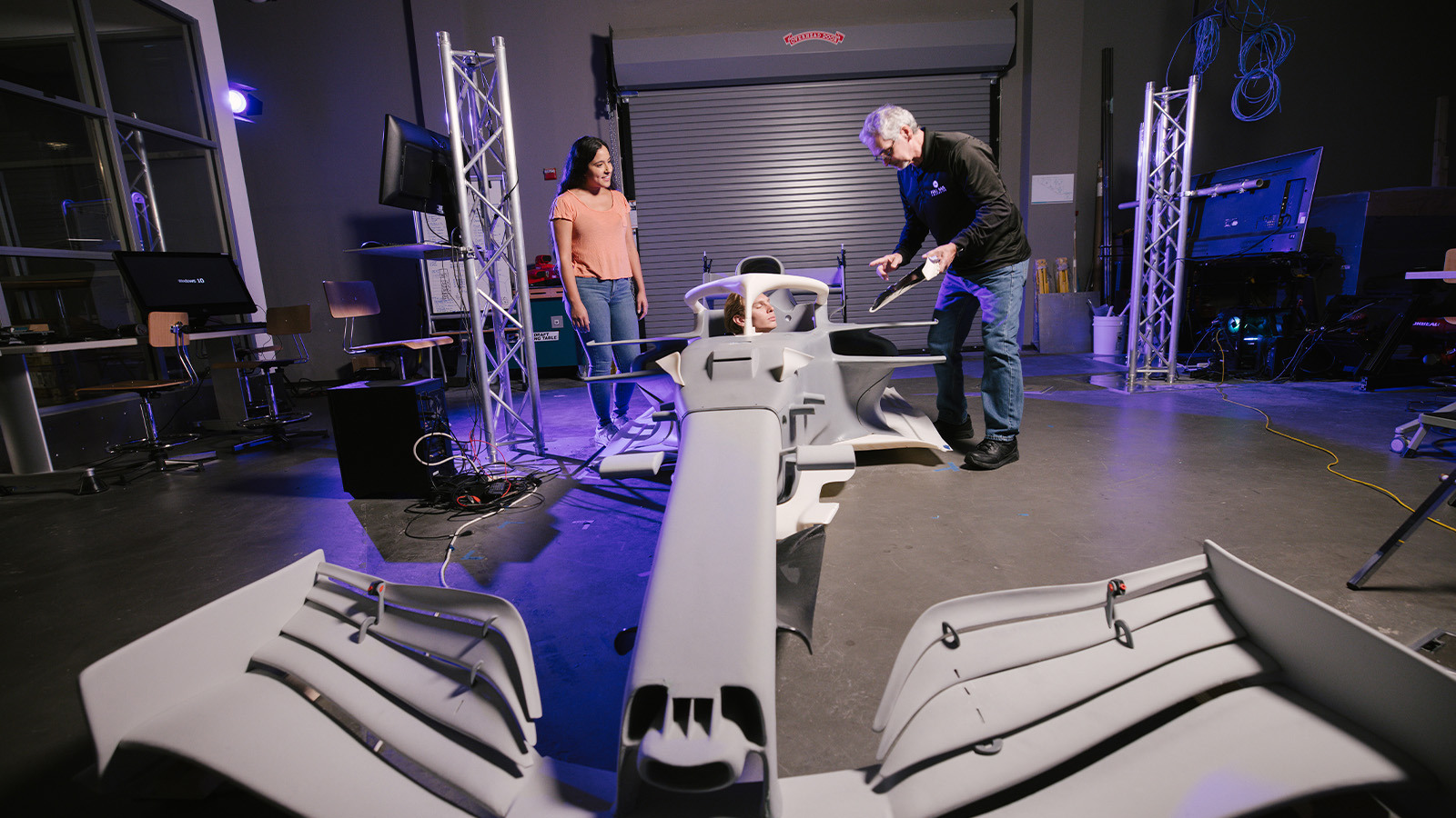 Students and an instructor work with a full-scale race car simulator model inside Full Sail’s Simulation Lab.