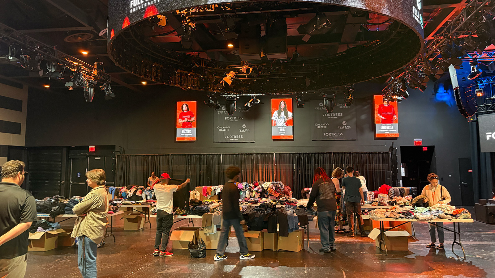 Tables of clothes fill the floor in the Fortress and students stand around looking through the clothing items.