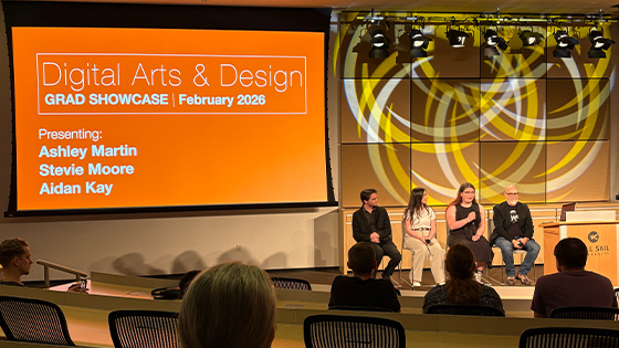 Aidan Kay, Stevie Moore, Ashley Martin, and Joel Sink sit in a row and present to an audience. A large screen behind them displays “Digital Arts & Design Grad Showcase February 2026” and a list of their names.