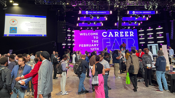 Students, alumni, and employers gather at the Full Sail Live venue for a career fair. A screen says, “Welcome to the February 12th Career Fair.”