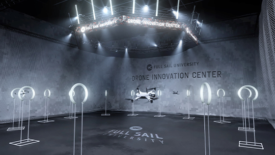 A white drone flies in the netted airspace in Full Sail’s Done Innovation Center. It is surrounded by white rings on stands.