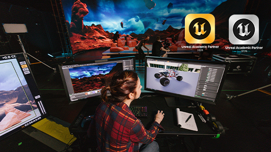 A student creates a space rover vehicle in Unreal Engine on a computer in Full Sail’s virtual production studio. A virtual background with a desert planet is on an LED wall in front of them.