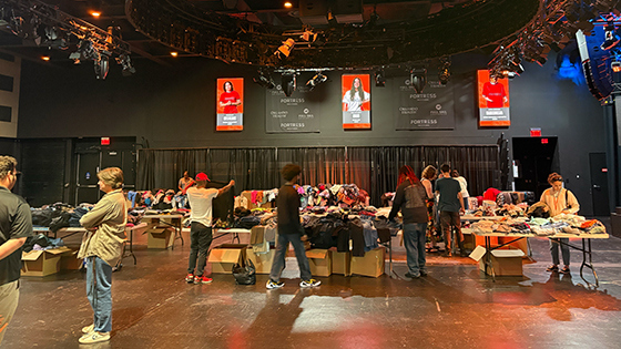 Tables of clothes fill the floor in the Fortress and students stand around looking through the clothing items.