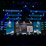 Two speakers stand on a stage in front of a large screen with the BSides Orlando logo displayed. Above it another screen displays the Full Sail University logo.