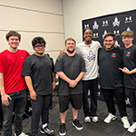 A group of five students, staff, and grads pose for a photo with NFL wide receiver Justin Jefferson in front of a step and repeat.