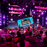Full Sail Live, lit in a purple hue, is filled with a crowd seated at workstations during the Unreal Fest Game Jam.