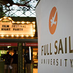 A Full Sail University banner is in focus in the foreground while the Enzian's lit-up marquee for the Florida Film Festival Opening Night Party appears in the background.