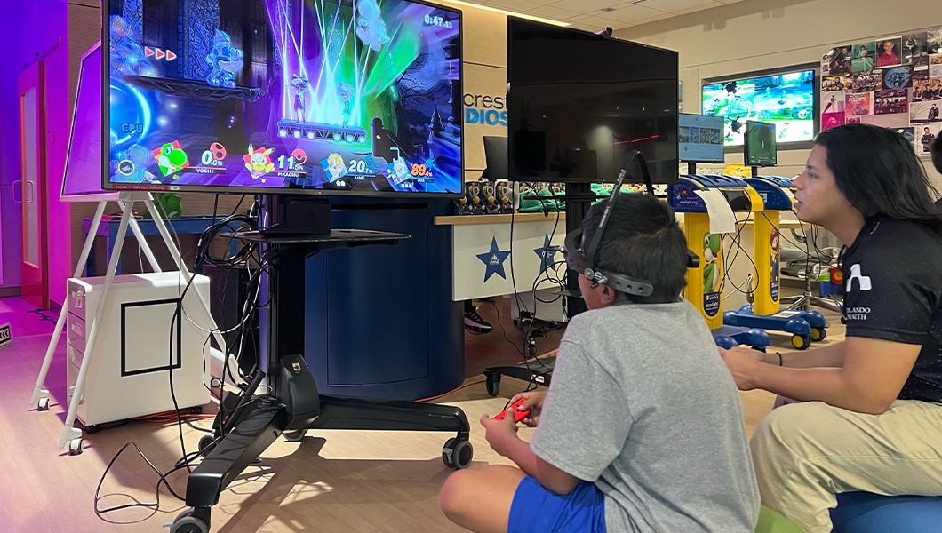 A Full Sail student and a patient sit at a video game console and play Super Smash Bros.