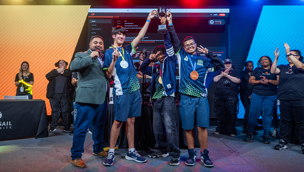 Winning high schoolers from Westside High pose on stage with their trophy and medals in the Full Sail University Orlando Health Fortress.