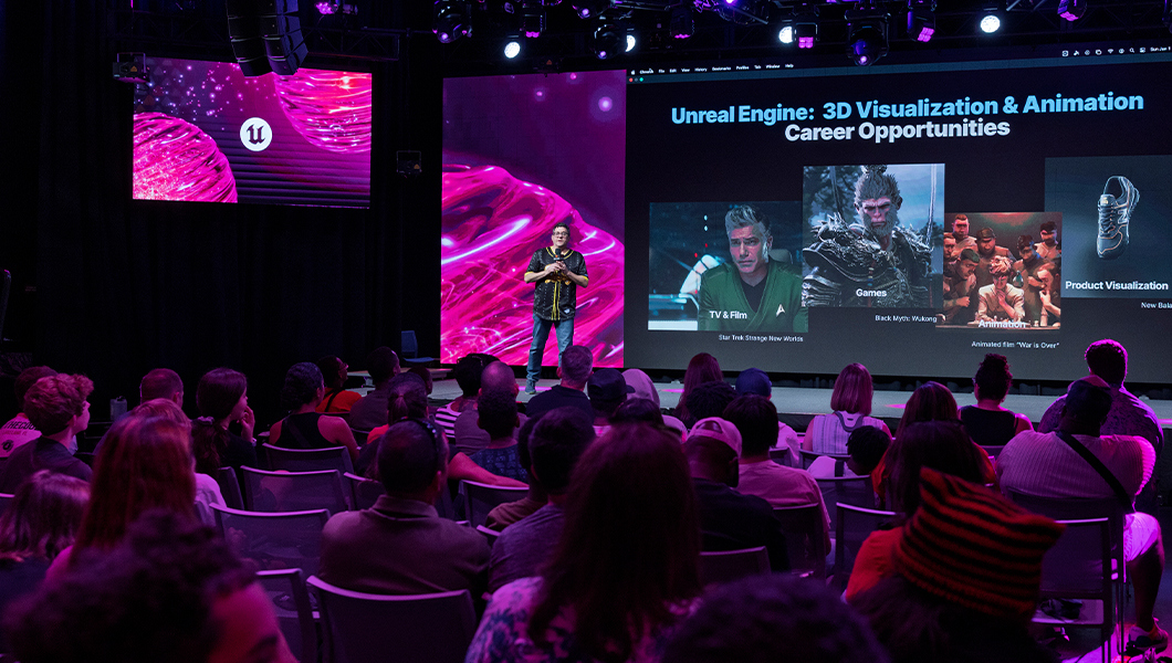 A speaker on stage in a venue of seated attendees, the large LED display behind him reads ‘Unreal Engine: 3D Visualization & Animation.’
