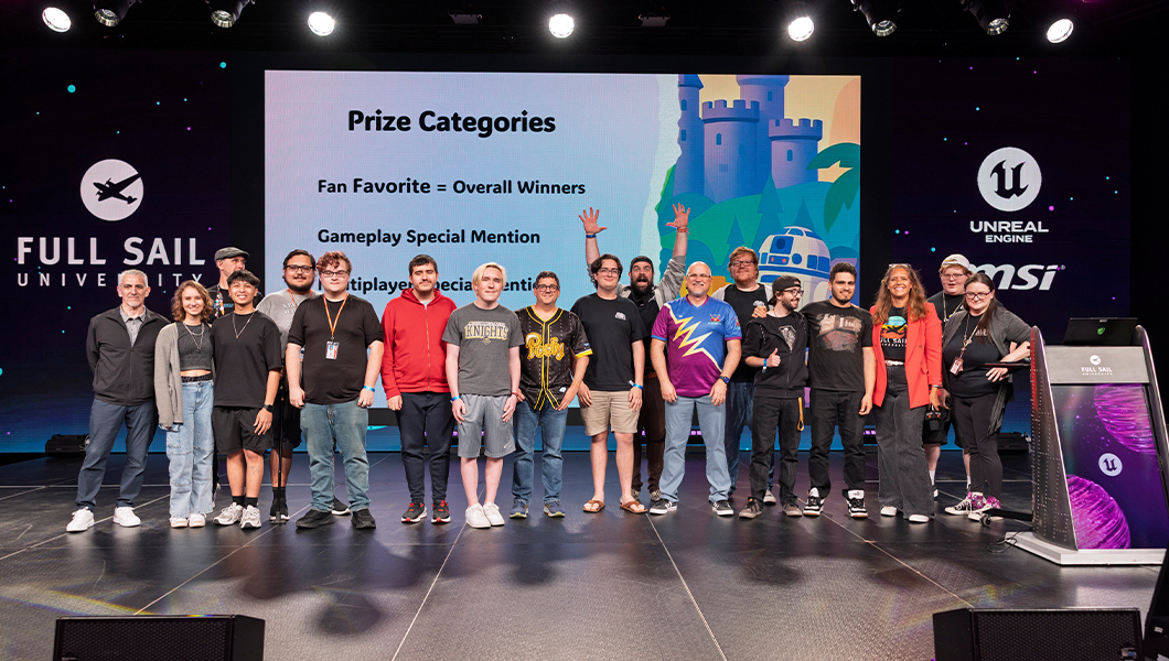A group of students, faculty, and event staff pose on stage together with ‘Prize Categories’ on the LED display behind them.