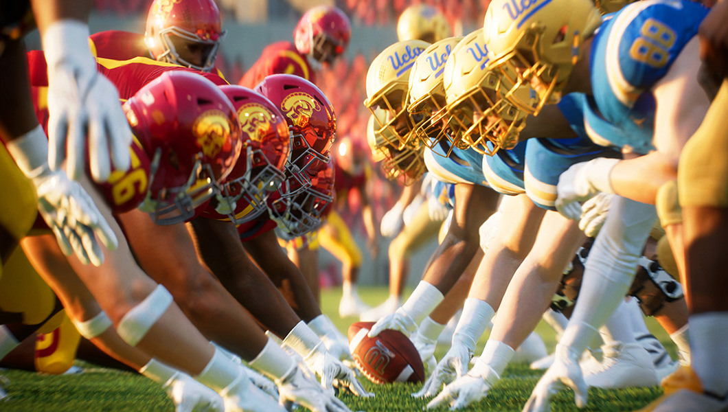 Two college football teams, USC in red and yellow and UCLA in blue and gold, face off at the line of scrimmage in a college football stadium.