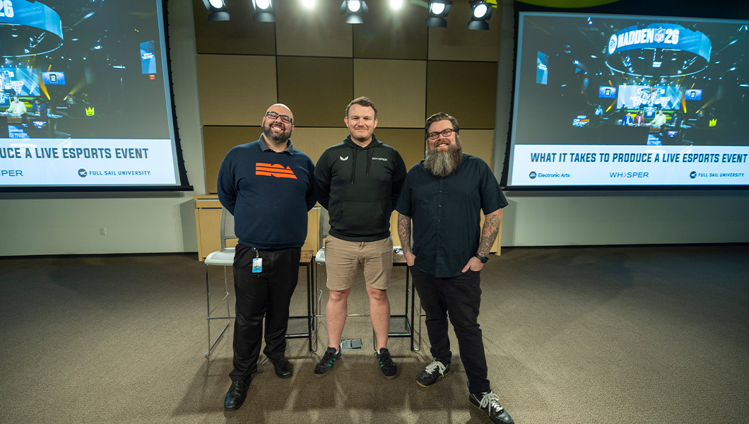 Three speakers pose between screens, reading “What It Takes to Produce a Live Esports Event,” under bright studio lights.
