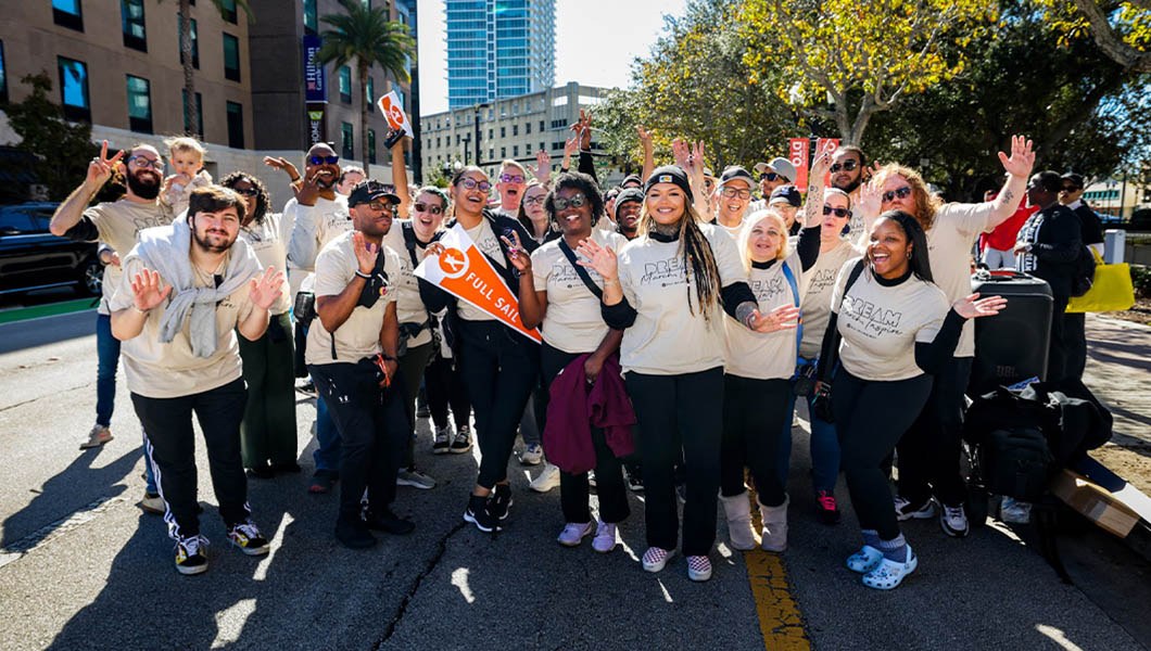 A group of staff, faculty, and students pose for a photo wearing “Dream, March, Inspire” t-shirts.