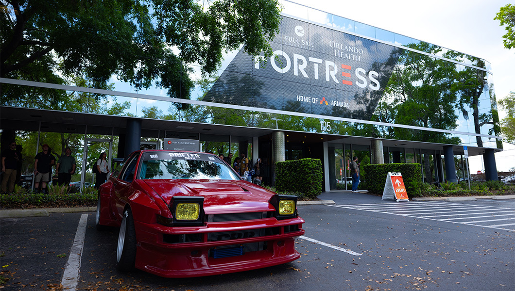 Lola, the car from ‘Drifter,’ parked outside the Full Sail Fortress, with event signage and attendees gathered near the entrance.
