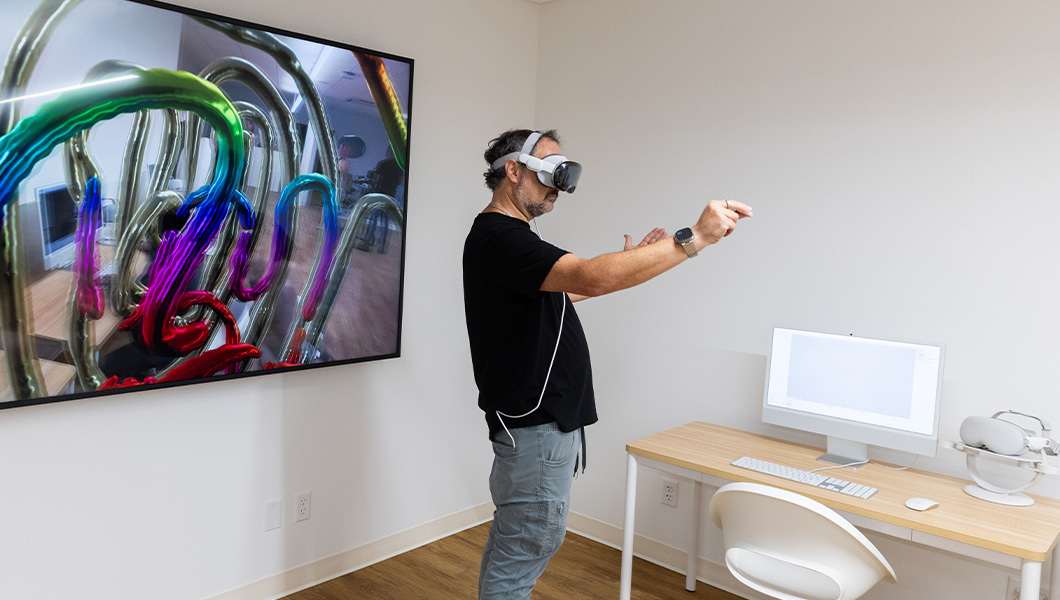 A user interacts with digital 3D visuals through a VR headset in Full Sail’s Spatial Computing Innovation Lab.