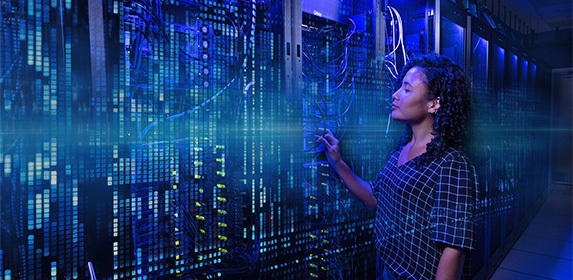 A student studying tech is seen standing in a large server room located on the Full Sail campus.