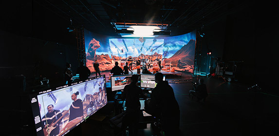 Students in Full Sail's Studio V1 virtual production studio during a live production in which a band is recording a music video against a sci-fi desert backdrop.