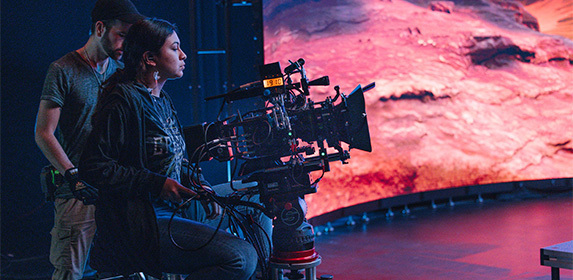 A film student works as a camera operator alongside another student during a live production in Full Sail's Studio V1 soundstage.
