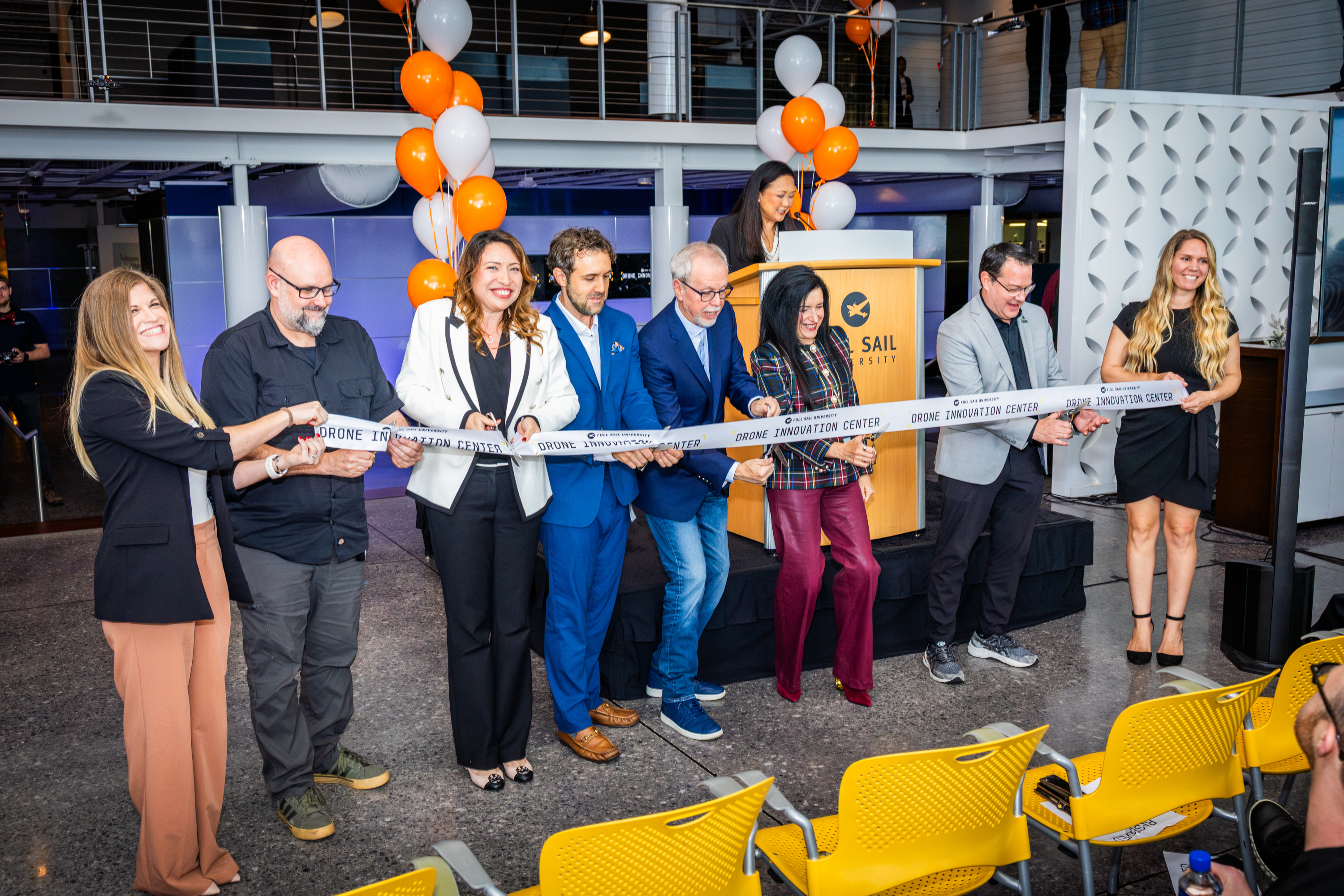 A group of people cutting a ceremonial ribbon at an event, symbolizing the opening of the Full Sail University Drone Innovation Center.